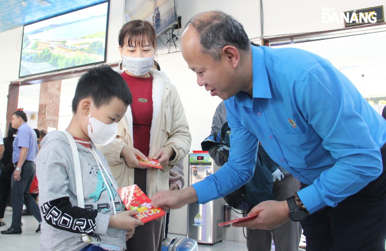 Phó Chủ tịch Liên đoàn Lao động thành phố Lê Văn Đại (bên phải) lì xì cho các gia đình người lam động tham gia “Chuyến tàu Công đoàn – Xuân 2025”. Ảnh: X.H