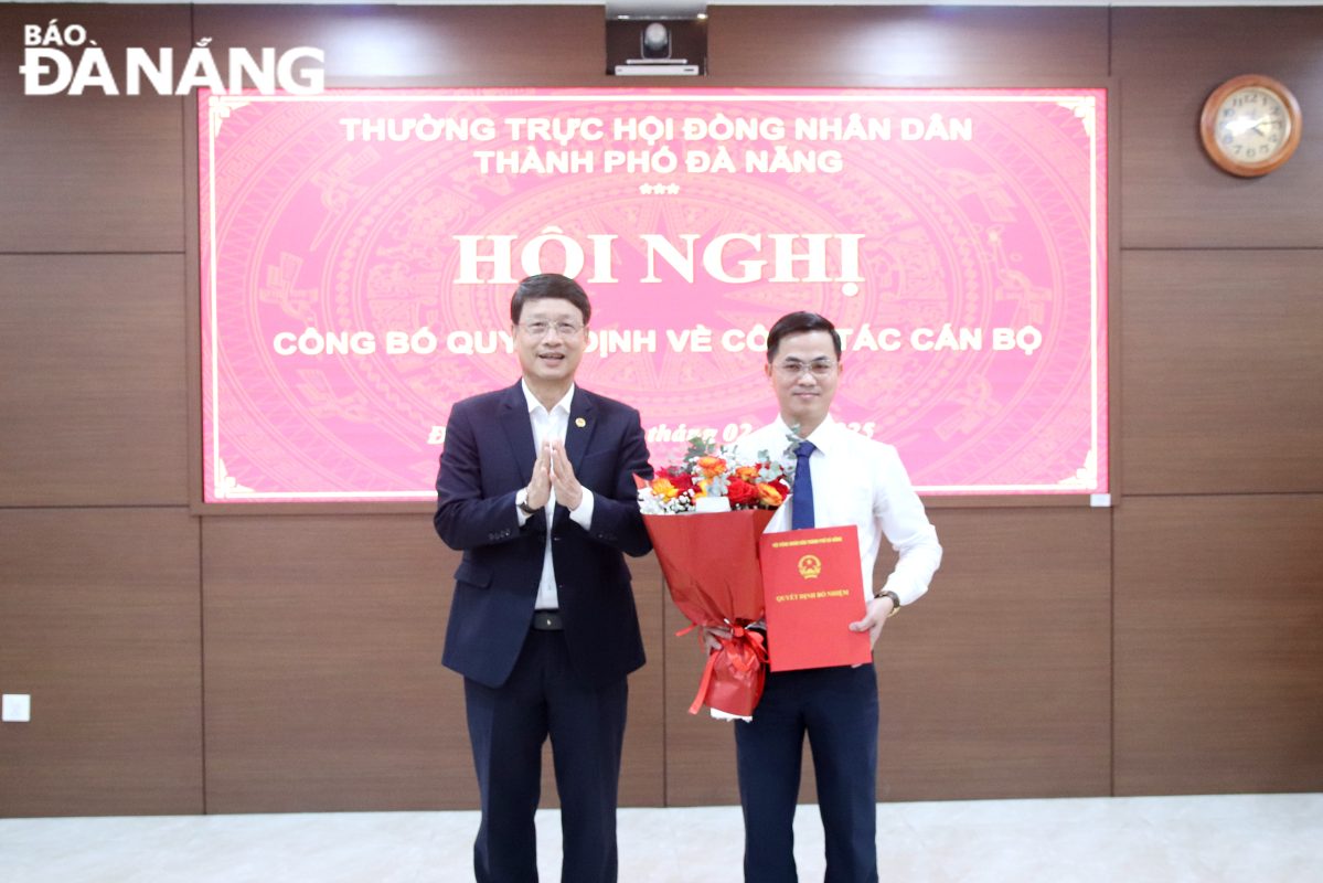 Chủ tịch HĐND thành phố Ngô Xuân Thắng (trái) trao quyết định, tặng hoa chúc mừng ông Hưng. Ảnh: T. HUY