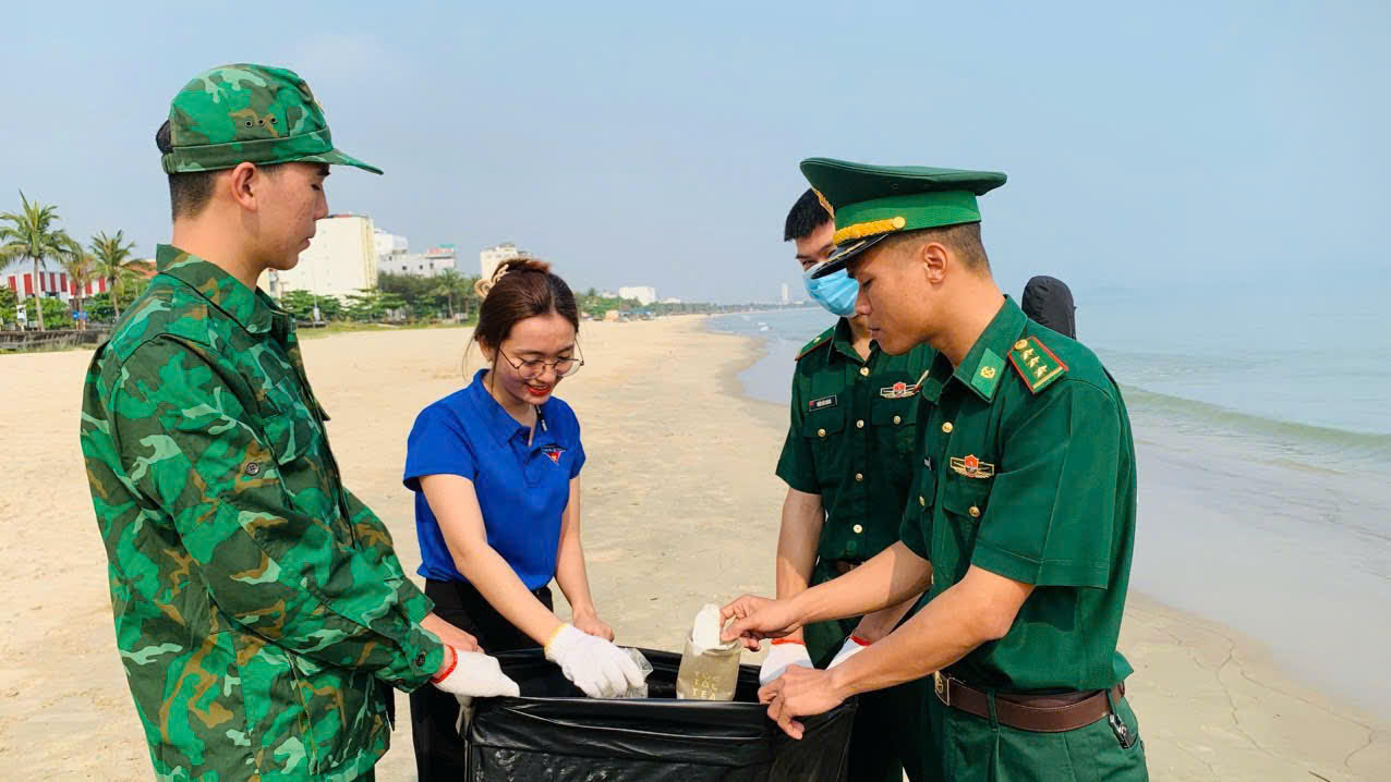 Thượng úy Nguyễn Trung Kiên (bên phải) và đồng đội tham gia làm sạch bãi biển dọc đường Nguyễn Tất Thành (quận Thanh Khê). Ảnh: DOÃN QUANG