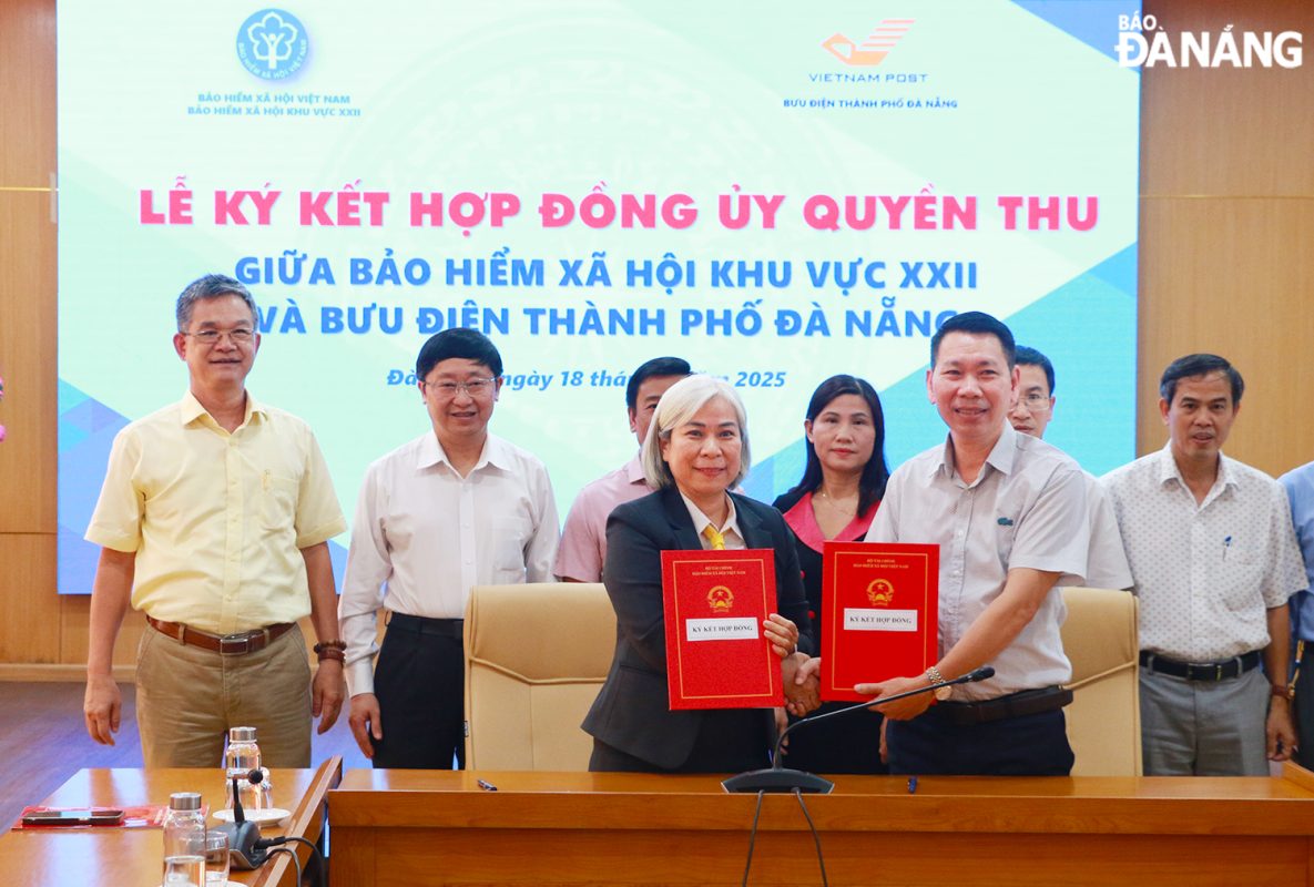 Giám đốc Bảo hiểm xã hội khu vực XXII Nguyễn Trí Đại (bên phải) ký kết hợp đồng ủy quyền thu với Bưu điện thành phố Đà Nẵng. Ảnh: T.PHƯƠNG