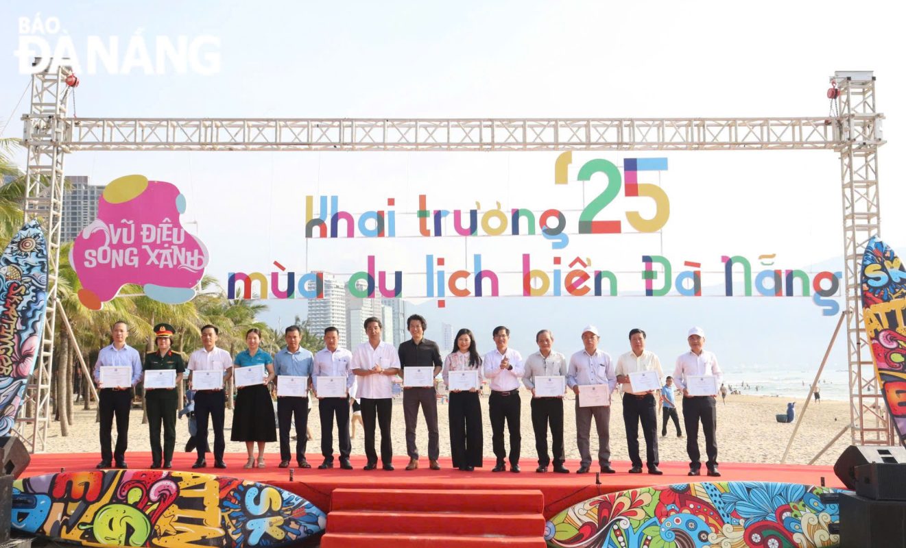 Phó Chủ tịch UBND thành phố Trần Chí Cường (thứ 7 từ trái qua) trao chứng nhận đồng hành cho các đơn vị tham gia trồng dừa tại bãi biển Đà Nẵng. Ảnh: NGỌC HÀ