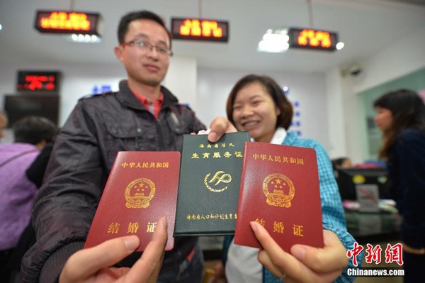 Trung Quốc đẩy mạnh đơn giản hóa quy trình đăng ký kết hôn. TRONG ẢNH: Một cặp đôi đang cầm Giấy chứng nhận kết hôn (màu đỏ) và Giấy chứng nhận sinh con (màu xanh lá cây).   Ảnh: Chinanews.com