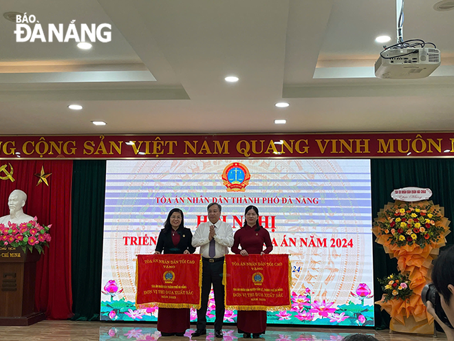 Lãnh đạo Tòa án nhân dân thành phố (bên trái) nhận cờ đơn vị thi đua xuất sắc. Ảnh: PV