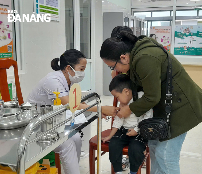 Nhân viên Trung tâm Kiểm soát bệnh tật thành phố tiêm vắc-xin phòng, chống sởi cho trẻ em.  Ảnh: LÊ HÙNG