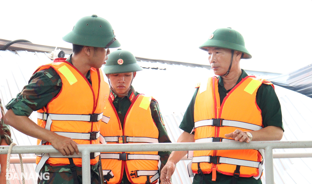 Đại tá Trần Quang Chánh (bìa phải), Phó Chỉ huy trưởng kiêm Tham mưu trưởng Bộ Chỉ huy Quân sự thành phố Đà Nẵng trực tiếp chỉ đạo tháo dỡ lồng bè bị mắc kẹt tại đập dâng An Trạch. Ảnh: HOÀNG HIỆP