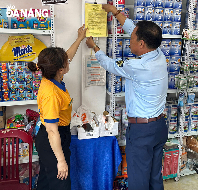 Cán bộ QLTT tuyên truyền cho các hộ kinh doanh cam kết bán hàng hoá có nguồn gốc xuất xưa