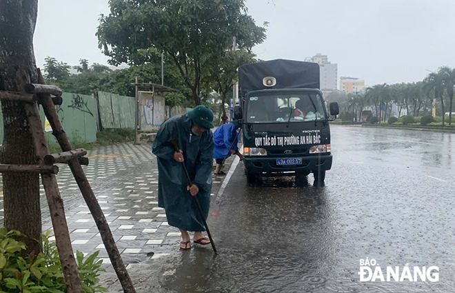 Các thành viên trong tổ phản ứng nhanh tại phường An Hải Bắc khơi thông cống rãnh, chống ngập lụt. Ảnh: tiến dũng