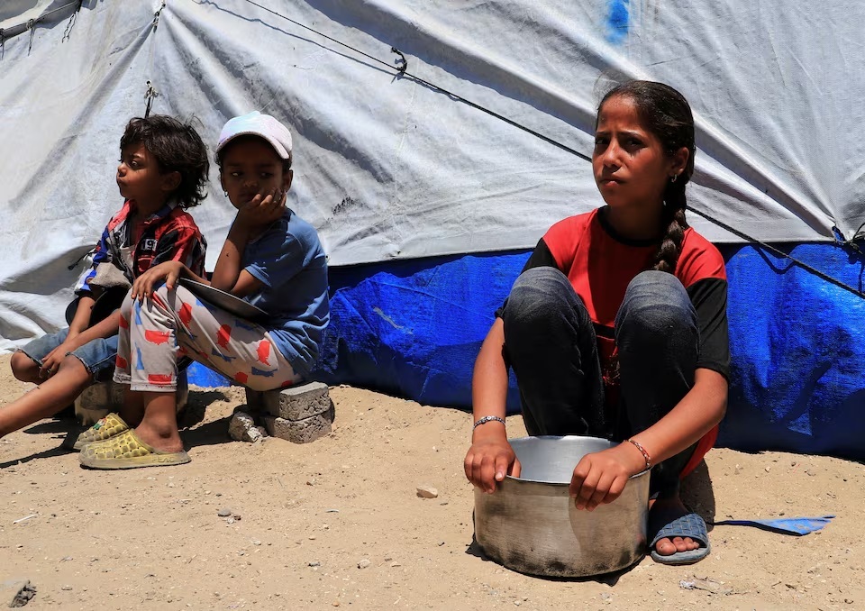 Trẻ em Palestine ngồi chờ nhận thức ăn từ bếp ăn từ thiện tại thành phố Gaza vào tháng 6 -2025. Ảnh: Reuters