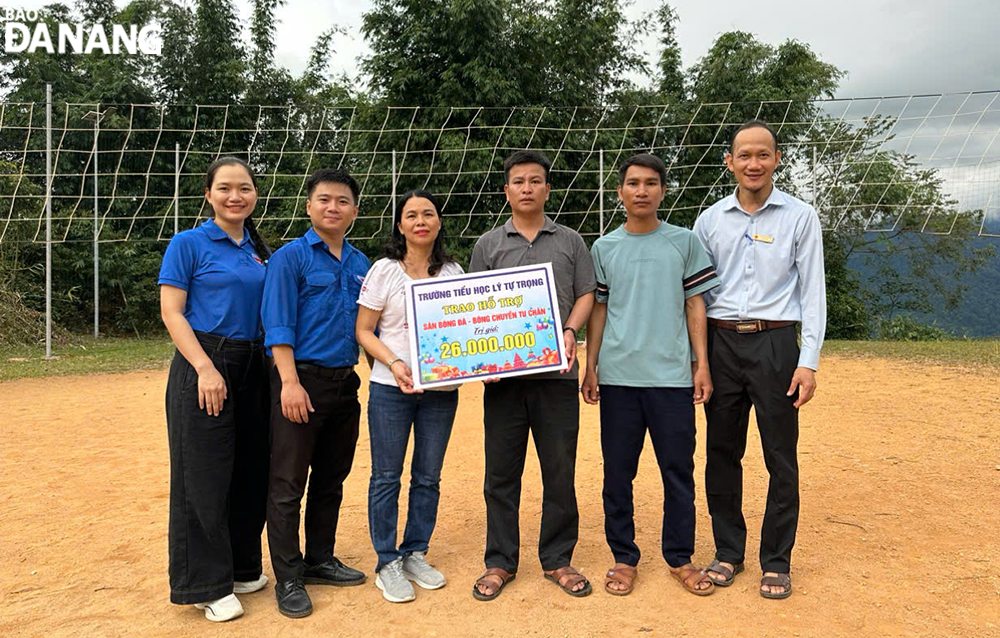 Đại diện Ban giám hiệu Trường Tiểu học Lý Tự Trọng (quận Hải Châu, Đà Nẵng) trao tặng tiền mặt để UBND xã Trà Cang làm sân bóng đá. Ảnh: BÌNH MINH